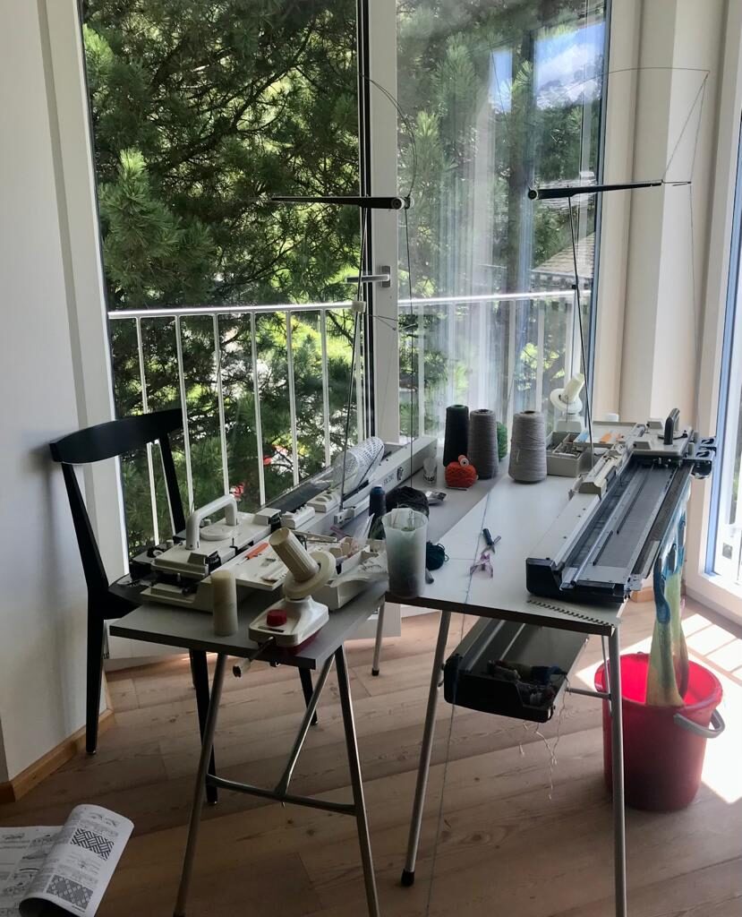 Helles Atelier mit Strickmaschinen an grossen Fenstern und Blick ins Grüne